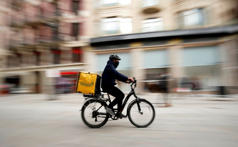 FILE PHOTO: Glovo deliver rider passes by a pedestrian area in Barcelona