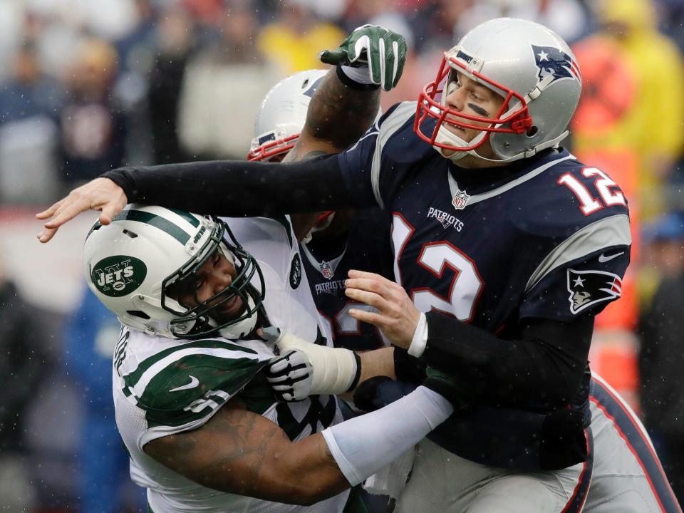 Tom Brady throws the ball as he gets hit by Jets players in 2016.