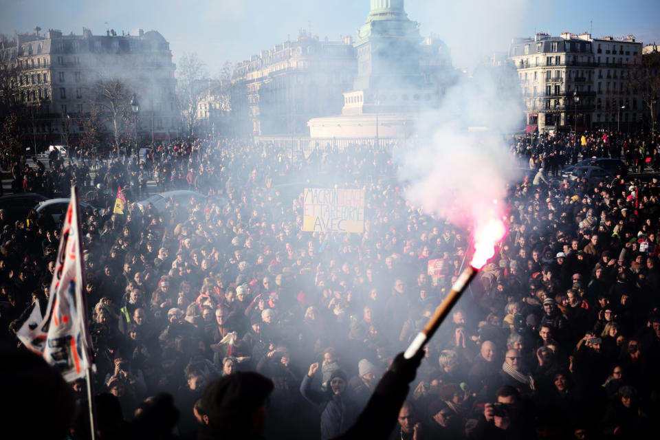 A worker holds a flare after a crowd on the Place de la Bastille listened to striking musicians of the Paris Opera house performing outside the Bastille Opera house Tuesday, Dec. 31, 2019 in Paris. (AP Photo/Kamil Zihnioglu)