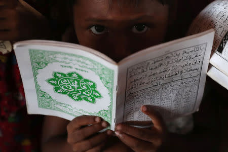 A young Rohingya refugee reacts to the camera while learning to recite the Koran in an Arabic school at Palongkhali makeshift refugee camp in Cox's Bazar, Bangladesh, November 7, 2017. REUTERS/Mohammad Ponir Hossain