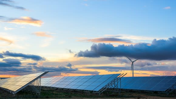 Solar arrays with a setting sun in the background.