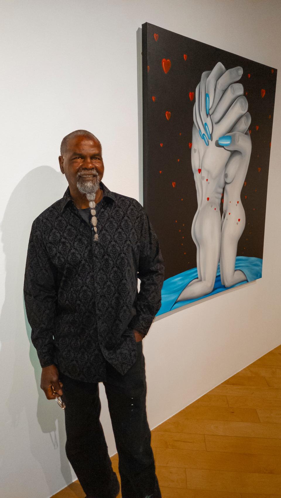 Artist, Mr. Wash, stands near one of his 'Hands of Time' paintings at The Palm Springs Art Museum.