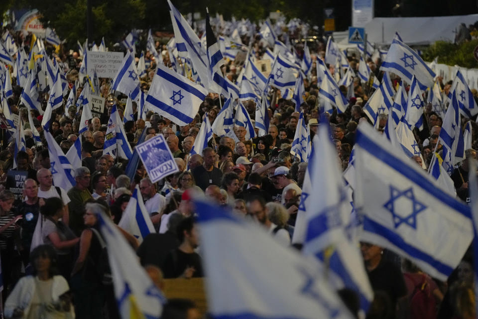 People wave Israeli flags during a protest against Israeli Prime Minister Benjamin Netanyahu's government, demanding new elections and the release of the hostages held in the Gaza Strip by the Hamas militant group, outside of the Knesset, Israel's parliament, in Jerusalem, Monday, June 17, 2024. (AP Photo/Ohad Zwigenberg)