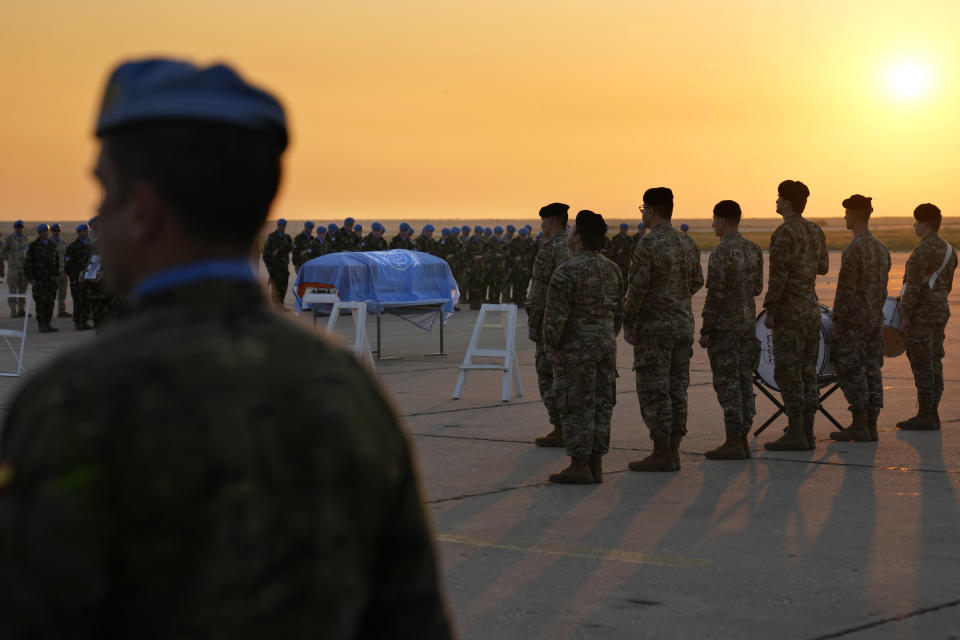 Lebanese soldiers, Irish and other nationalities U.N. peacekeepers, stand around the coffin draped by the United Nations flag of their comrade Pvt. Seán Rooney who was killed during a confrontation with residents near the southern town of Al-Aqbiya on Wednesday night, during his memorial procession at the Lebanese army airbase, at Beirut airport, Sunday, Dec. 18, 2022. (AP Photo/Hussein Malla)