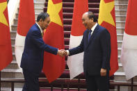 Japan's Prime Minister Yoshihide Suga, left, shakes hands with Vietnam's Prime Minister Nguyen Xuan Phuc after the exchange of documents at the Government Office in Hanoi Monday, Oct. 19, 2020. (Nhac Nguyen/Pool Photo via AP)