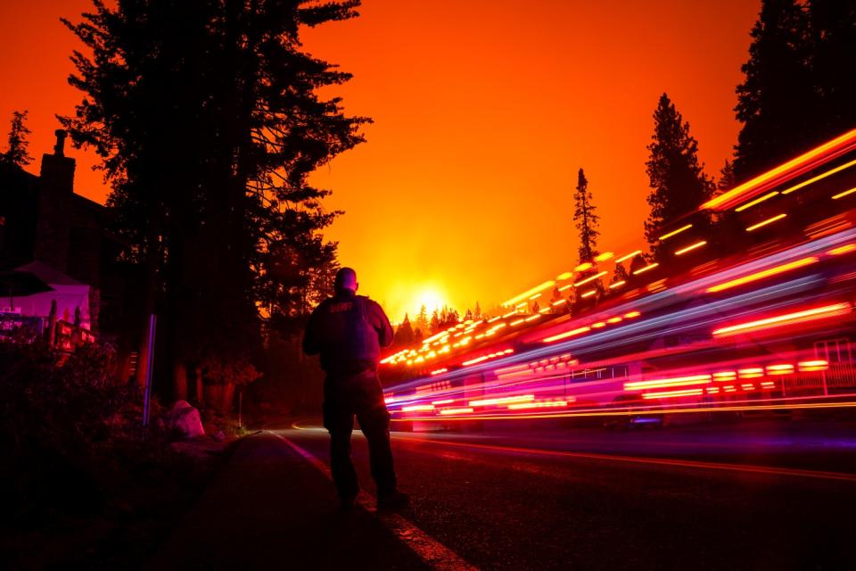 A vehicle streaks by in a long exposure as Fresno County sheriff's Deputy Jeffery Shipman stands along State Route 168.