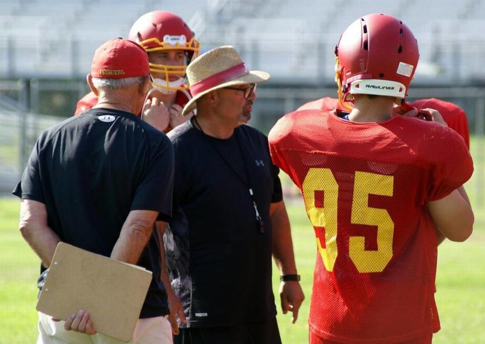 Head coach Ron Garcia, center, and assistant Charlie Casale, left, work with members of the Coast Union football team during preseason workouts in late August 2017.