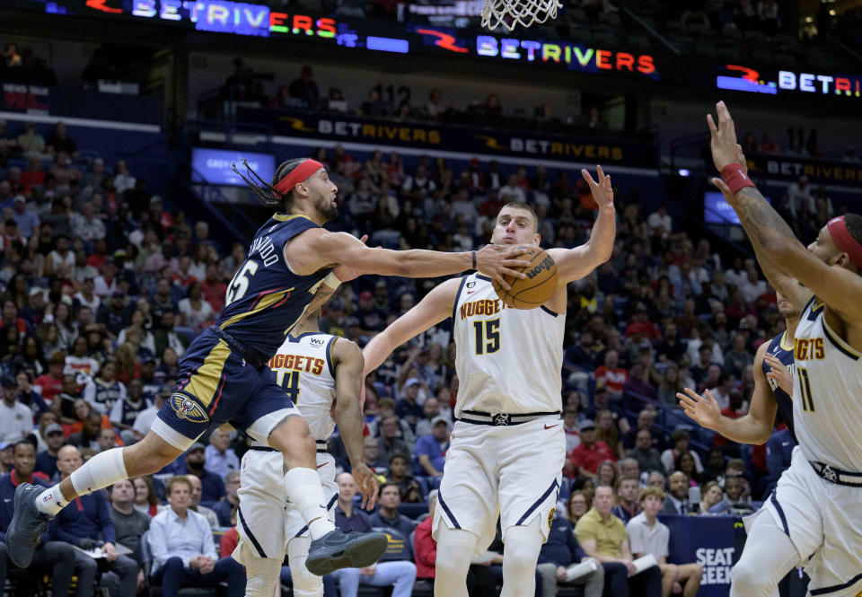 New Orleans Pelicans guard Jose Alvarado, front left, passes the ball around Denver Nuggets center Nikola Jokic, center, in the first half of an NBA basketball game in New Orleans, Sunday, Dec. 4, 2022. (AP Photo/Matthew Hinton)