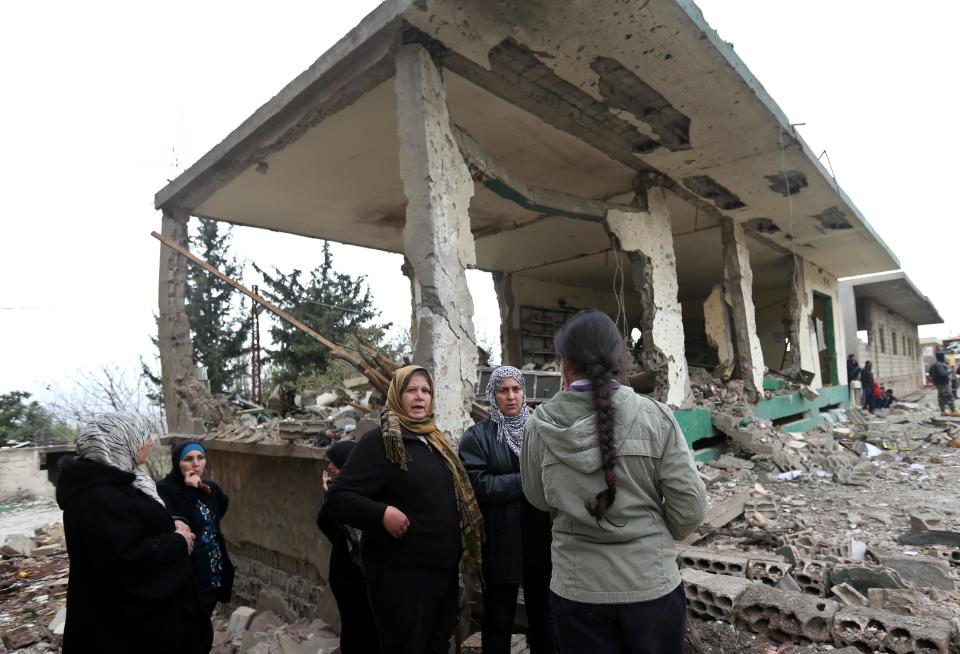 Lebanese women gather in front of damaged shops at the site of a deadly car bombing Sunday night, in the town of Nabi Othman, about 30 kilometers (18 miles) north of Baalbek, northeast Lebanon, Monday March 17, 2014. Lebanese security officials said the explosion killed at least two people and caused panic and massive destruction in the Hezbollah stronghold, which has a sizable Christian population in addition to Shiites. The civil war in neighboring Syria already has ignited polarizing sectarian tensions between Lebanon's Sunnis and Shiites. (AP Photo/Hussein Malla)