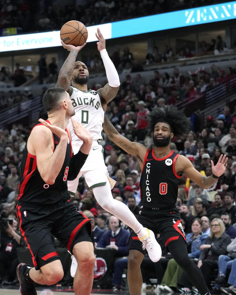 Milwaukee Bucks' Damian Lillard shoots as Chicago Bulls' Coby White (0) and Nikola Vucevic defend during the first half of an NBA basketball game Friday, March 1, 2024, in Chicago. (AP Photo/Charles Rex Arbogast)