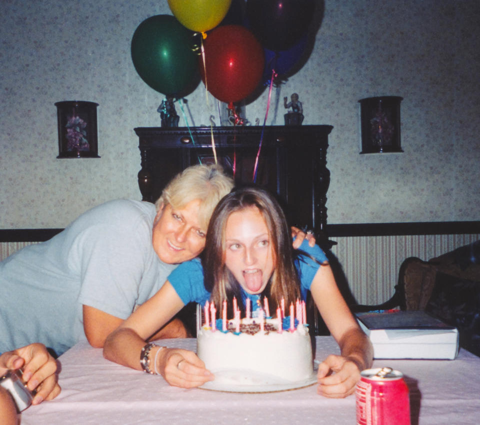 A girl about to blow her birthday candles out as her mom hugs her