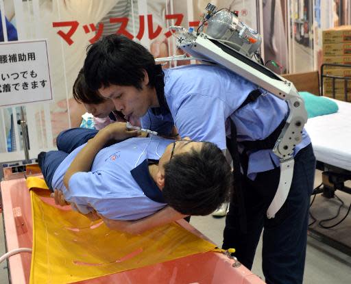 A Japanese elderly care company Asahi Sun Clean employee (top) wearing a power suit, called 'Muscle Suit,' lifts a fellow worker during a demonstration at the annual Internatinal Robot Exhibition in Tokyo, on November 6, 2013