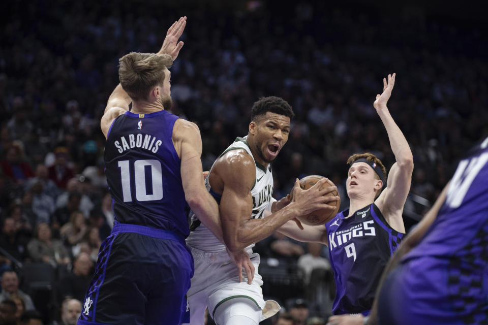 Milwaukee Bucks forward Giannis Antetokounmpo (34) splits Sacramento Kings forward Domantas Sabonis (10) and guard Kevin Huerter (9) as he drives to the basket in the first quarter of an NBA basketball game in Sacramento, Calif., Tuesday, March 12, 2024. (AP Photo/José Luis Villegas)