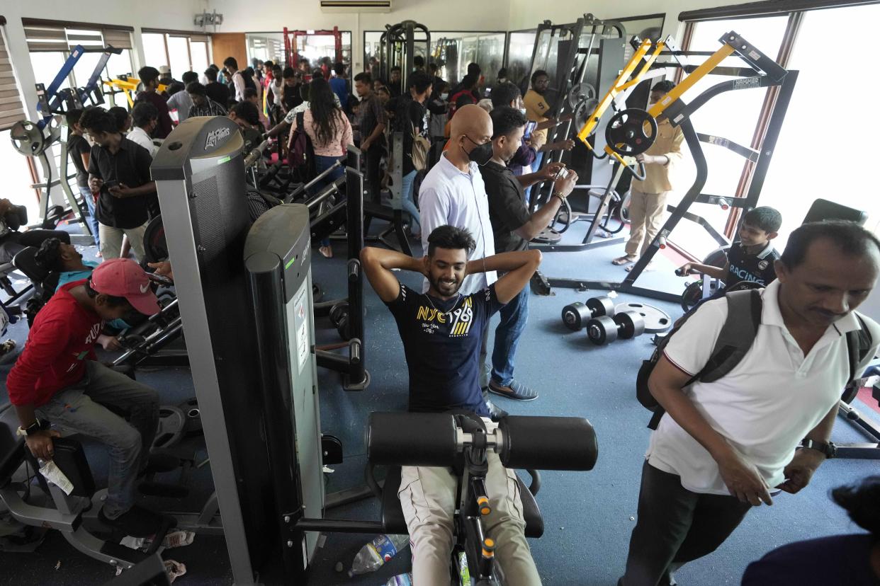 People use gym equipment as they throng President Gotabaya Rajapaksa's official residence on the second day after it was stormed in Colombo, Sri Lanka, Monday, July 11, 2022. Sri Lanka is in a political vacuum for a second day Monday with opposition leaders yet to agree on who should replace its roundly rejected leaders, whose residences are occupied by protesters, angry over the country's economic woes.(AP Photo/Eranga Jayawardena)