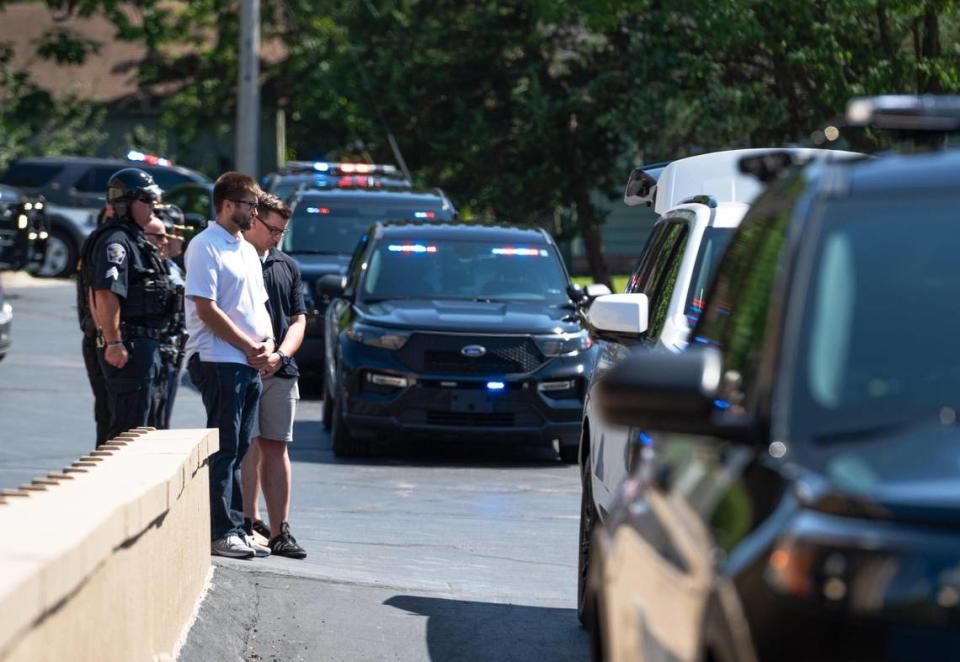 Mourners bow their heads Tuesday, Aug. 8, 2023, as the remains of Officer Jonah Oswald are moved into the Amos Family Funeral Home and Crematory in Shawnee. Oswald was killed after a shooting unfolded inside of a QuikTrip on Sunday, Aug. 6, 2023, in Mission.