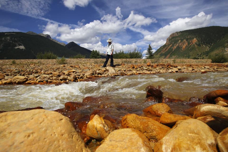 Melanie Bergolc, a resident of Silverton, Colorado, walks along the banks of Cement Creek in Silverton on Aug. 10, 2015, where residue from the Gold King Mine spill is evident.