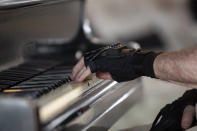 Brazilian pianist Joao Carlos Martins plays the piano wearing bionic gloves at his home in Sao Paulo, Brazil, Wednesday, Jan. 22, 2020. Martins, 79, was for decades Brazil's most acclaimed pianist, but an accident an a degenerative disease forced him to stop playing with both hands since 1998. That changed a few months ago when a new friend came to him with a pair bionic gloves that suit him perfectly. He can now play again with nine out of ten fingers. (AP Photo/Andre Penner)