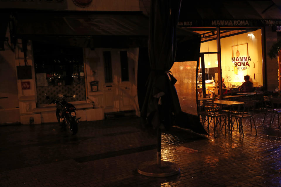 People eat in an Italian restaurant next to a closed Greek bar, left, in Brussels, Thursday, Oct. 8, 2020. Since bars in Brussels were forced to close as of Thursday for at least a month to deal with a massive surge in cases while restaurants were allowed to remain open, the big question on the streets is: when is a bar a bar and when is a bar a restaurant. (AP Photo/Francisco Seco)