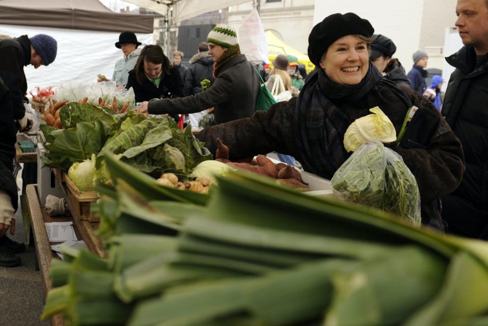 Alice Waters looks over rows of vegetables.