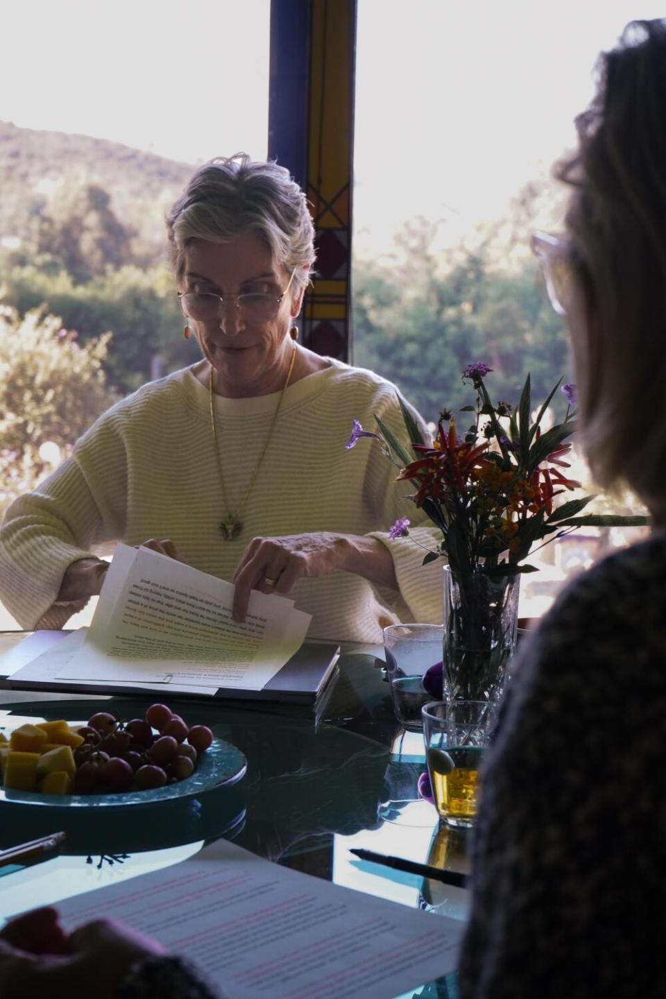 A woman sitting at a dining table shuffling through paper.