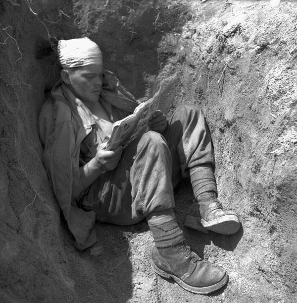 Private G.U.I. Lambert, 2nd Battalion, Royal 22nd Regiment, reads a comic book in a slit trench, Korea, May 28, 1951.