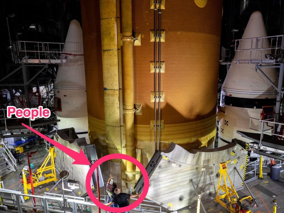 two people stand on a platform halfway up a giant rocket