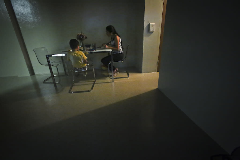 A domestic violence survivor sits with her son for dinner in their new, sparsely furnished apartment in New York.