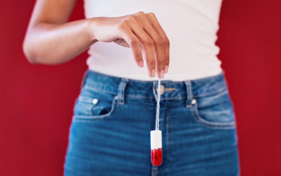 Woman holding a tampon that's been dipped in red liquid