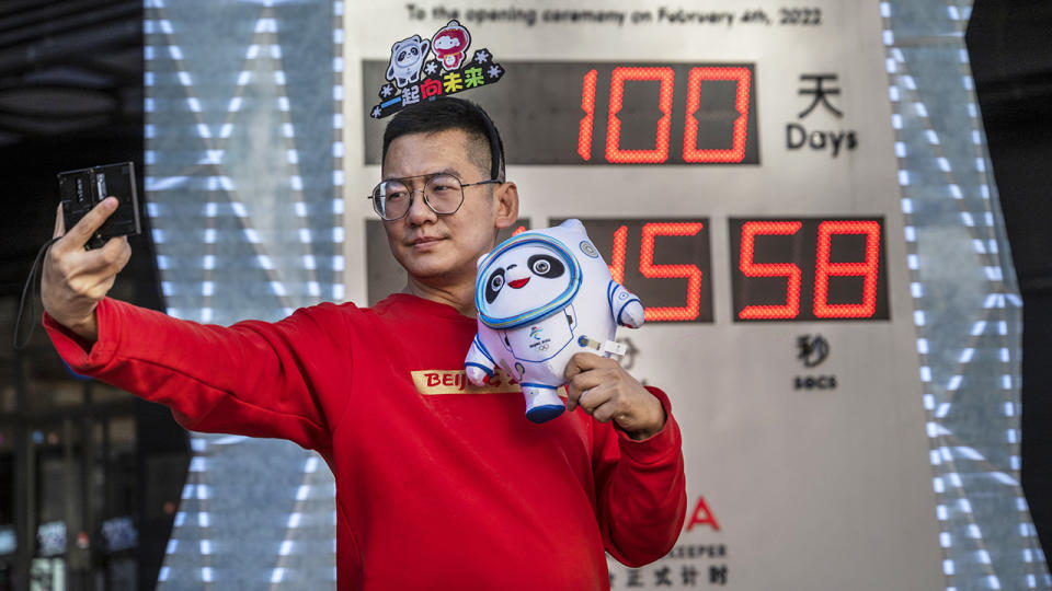 A man, pictured here taking a selfie next to a countdown screen showing 100 days before the opening of the Beijing 2022 Winter Olympics.