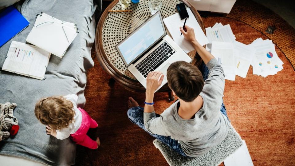 Hombre trabajando desde casa con su hija al lado