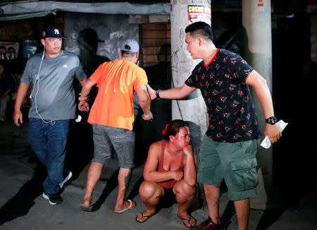 Plainclothes police officer hold a man as they comfort him after his brother, who police say was killed in a spate of drug-related violence overnight, was shot to death in Manila, Philippines August 16, 2017. REUTERS/Dondi Tawatao