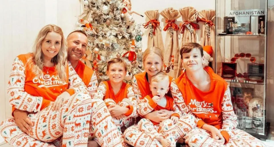 Shawn and Kat Dell with their four young children in christmas pjs. 