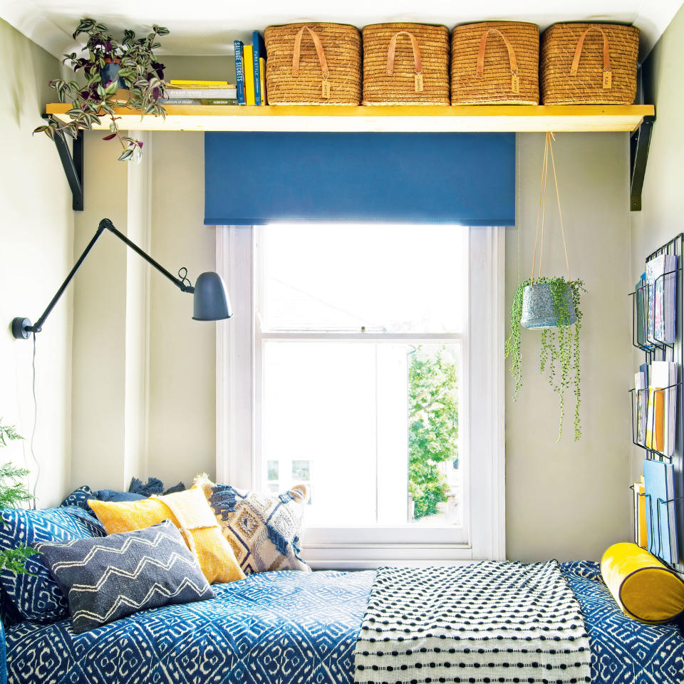 small bedroom with storage baskets high up above bed