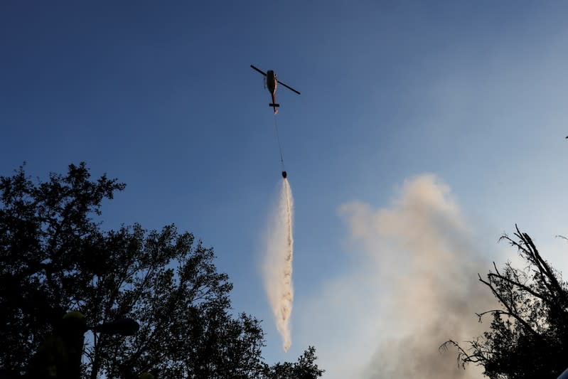 A helicopter makes a water drop on a burning structure during the Kincade fire in Calistoga, California