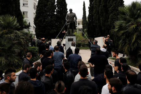 A statue of former U.S. president Harry Truman is tied with ropes as a supporter of the Greek Communist Party uses a grinder in a effort to bring the statue down during a demonstration against air strikes on Syria by the United States, Britain and France, in Athens, Greece April 16, 2018. REUTERS/Alkis Konstantinidis
