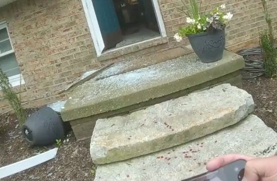 In this image from body-worn camera, a Summit County Sheriff's deputy takes picture of a broken storm door and a flower pot that was knocked over July 7 during a domestic dispute at the home of a relative of Rep. Bob Young, R-Green. Green was indicted on two first-degree misdemeanors for domestic violence the night before and assault for this incident where a relative blocked him from entering his home. Blood is visible on the steps.