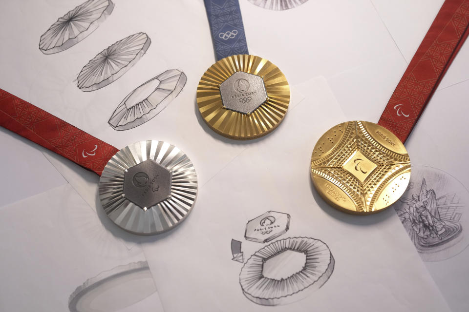 The Paris 2024 Olympic gold medal, center, the Paris 2024 Paralympic, gold medal, right, and silver medal, left, are presented to the press, in Paris, Thursday, Feb. 1, 2024. A hexagonal, polished piece of iron taken from the Eiffel Tower is being embedded in each gold, silver and bronze medal that will be hung around athletes' necks at the July 26-Aug. 11 Paris Games and Paralympics that follow. (AP Photo/Thibault Camus)