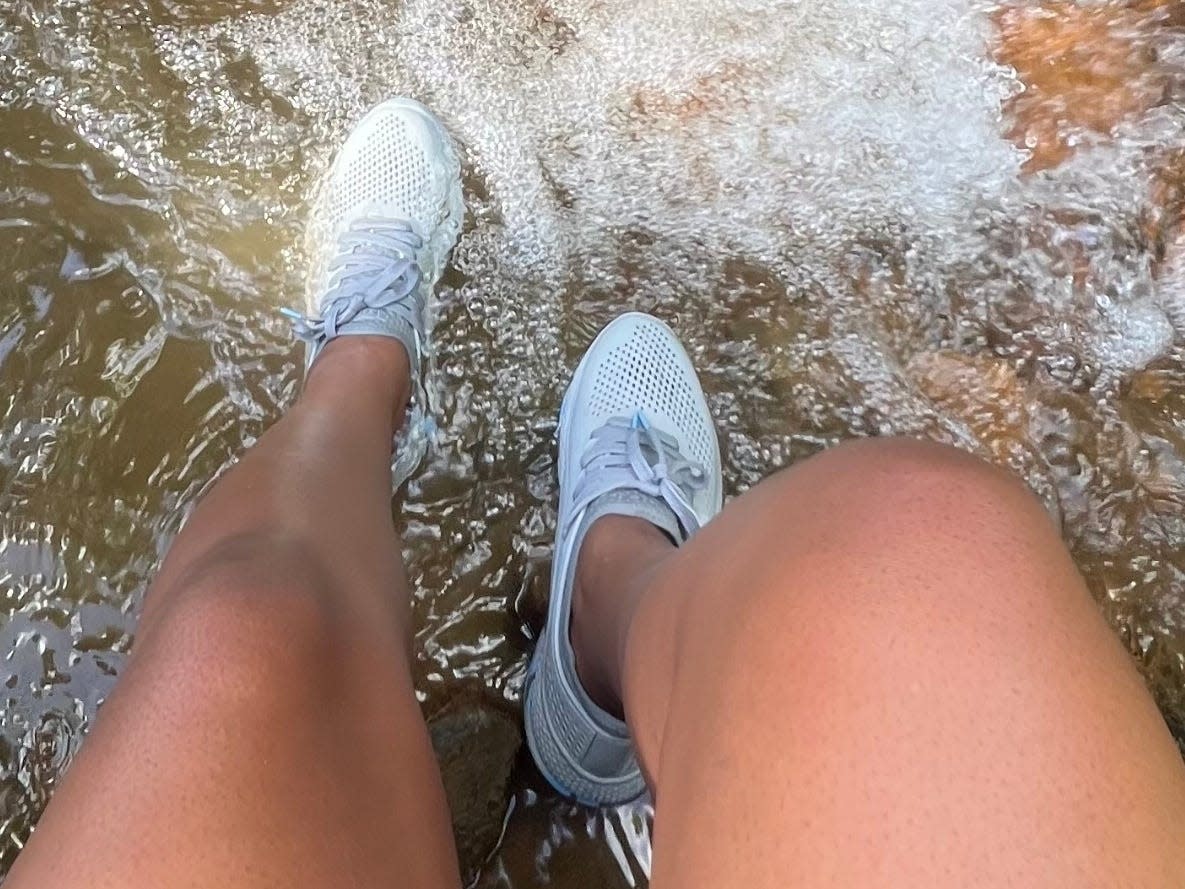 Mariette wearing blue water sneakers, stepping into running water.