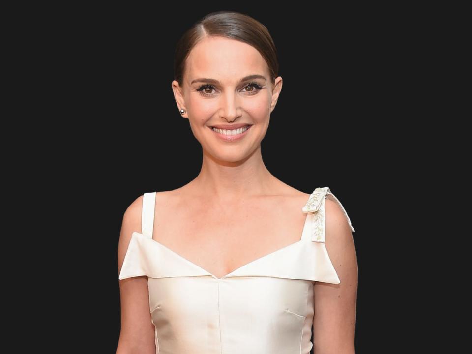 Natalie Portman wears a white dress and smiles at the camera.