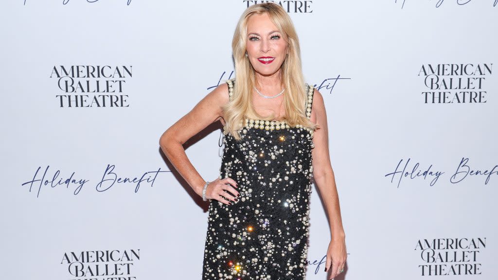 Sutton Stracke posing with her hand on her hip, smiling, and wearing a black and white dress.