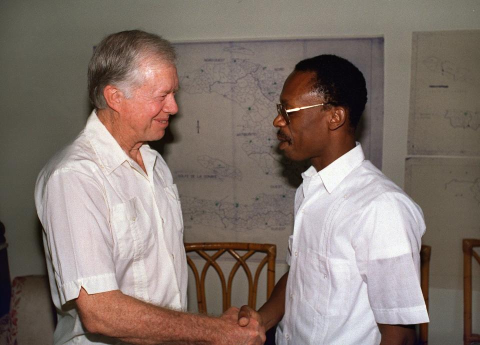 Former President Jimmy Carter greets Haitian presidential candidate Jean-Bertrand Aristide on the eve of the Haitian presidential elections in 1990. Carter led an international team of observers that monitored the election process. <a href="https://www.gettyimages.com/detail/news-photo/former-us-president-jimmy-carter-greets-haitian-news-photo/481997355?phrase=jimmy%20carter%20in%20haiti&adppopup=true" rel="nofollow noopener" target="_blank" data-ylk="slk:Thony Belizaire/AFP via Getty Images;elm:context_link;itc:0;sec:content-canvas" class="link ">Thony Belizaire/AFP via Getty Images</a>