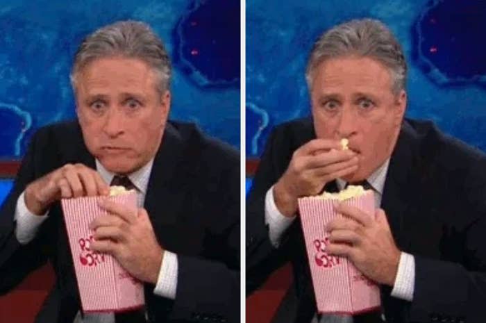 Jon Stewart eats popcorn, appearing intrigued and focused in a split-panel image