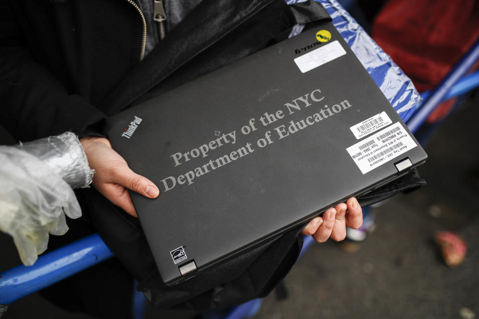 Anna Louisa, 18, receives her school laptop for home study at the Lower East Side Preparatory School Thursday, March 19, 2020, in New York, as coronavirus restrictions shuttered classrooms throughout the city. New York Gov. Andrew Cuomo tightened work-from-home rules as confirmed cases continued to climb in New York, an expected jump as testing becomes more widespread. (AP Photo/John Minchillo)