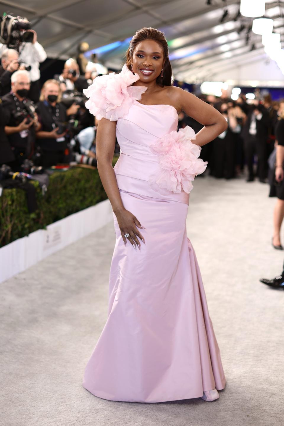 Jennifer in a light pink mermaid style dress with one shoulder with voluminous flowers.