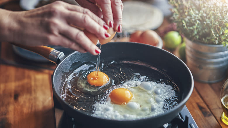 cracking eggs into pan with oil