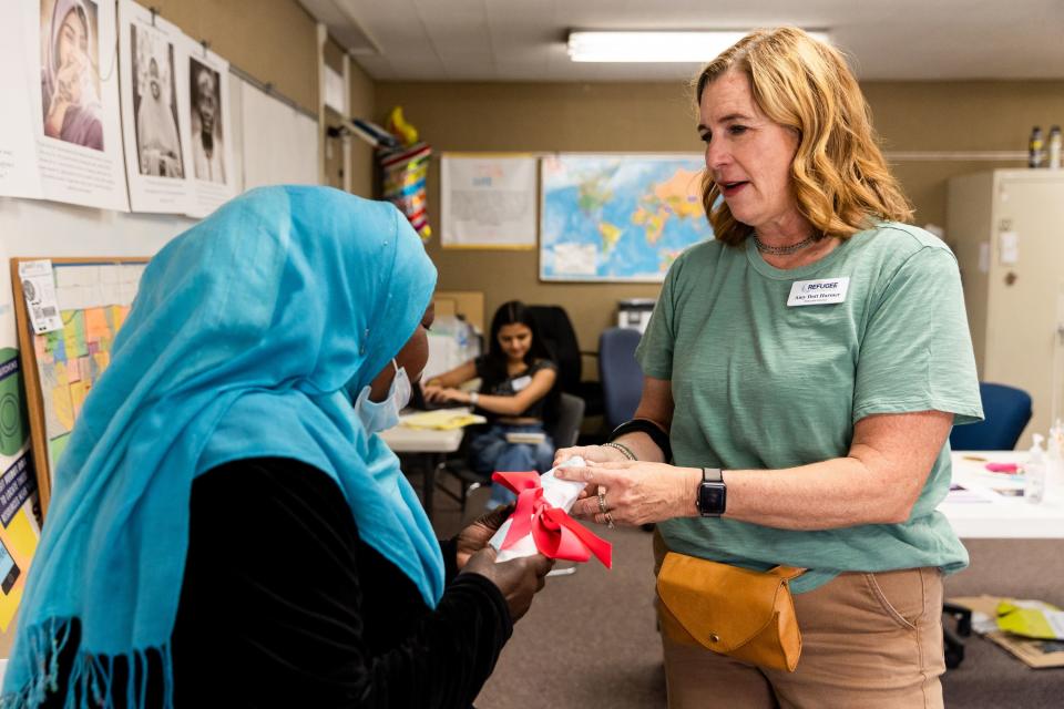 Zinab, from Sudan, left, gets an apron from Amy Dott Harmer, executive director for the Utah Refugee Connection, at the Serve Refugees Sharehouse.