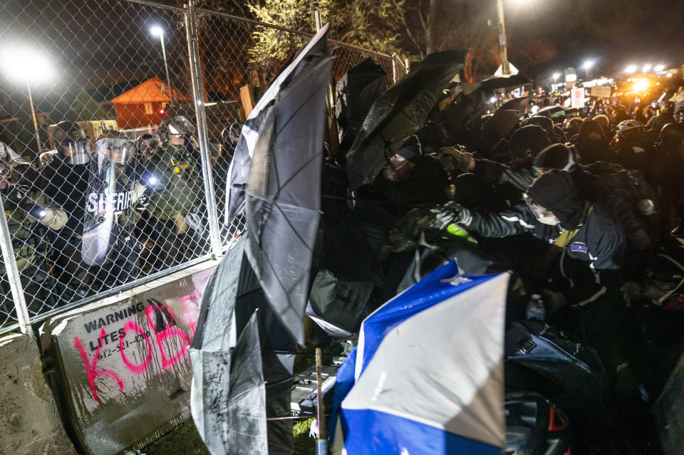 Demonstrators use umbrellas to press against a perimeter security fence and agitate authorities during a protest decrying the shooting death of Daunte Wright outside the Brooklyn Center Police Department, Wednesday, April 14, 2021, in Brooklyn Center, Minn. (AP Photo/John Minchillo)