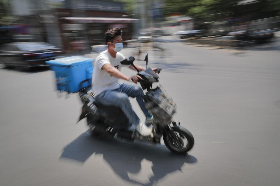 A food delivery worker wearing a protective face mask to help curb the spread of the new coronavirus rides on a street in Beijing, Sunday, June 21, 2020. According to state media reports, nearly one hundred thousand delivery workers have to accept the nucleic acid testing, a countermeasure to prevent the spread of the virus in the capital city. (AP Photo/Andy Wong)