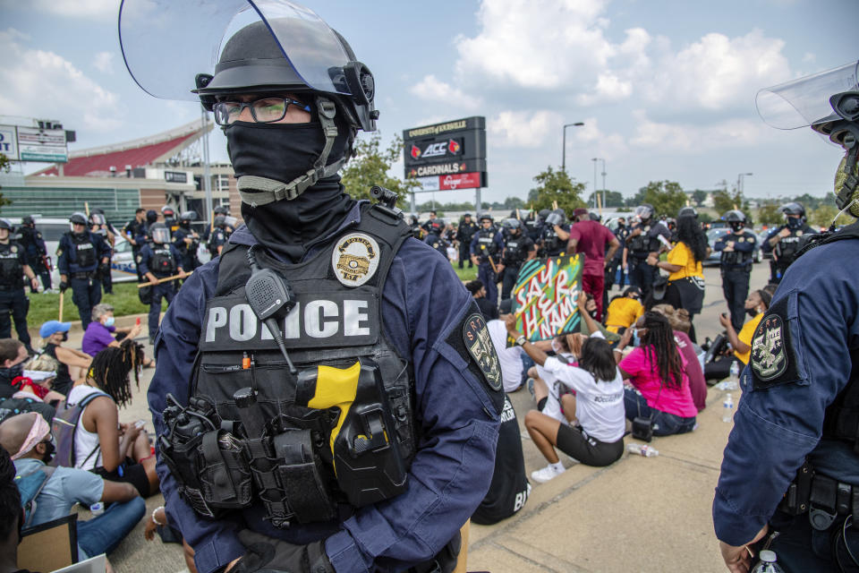 A police officer stands guard as protesters sit down during the Good Trouble Tuesday march for Breonna Taylor, Tuesday, Aug. 25, 2020, in Louisville, Ky. (Amy Harris/Invision/AP)d
