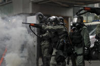 Riot policemen point weapons during a confrontation with demonstrators during a protest in Hong Kong, Sunday, Aug. 25, 2019. Hong Kong police have rolled out water cannon trucks for the first time in this summer's pro-democracy protests. The two trucks moved forward with riot officers Sunday evening as they pushed protesters back along a street in the outlying Tsuen Wan district. (AP Photo/Kin Cheung)